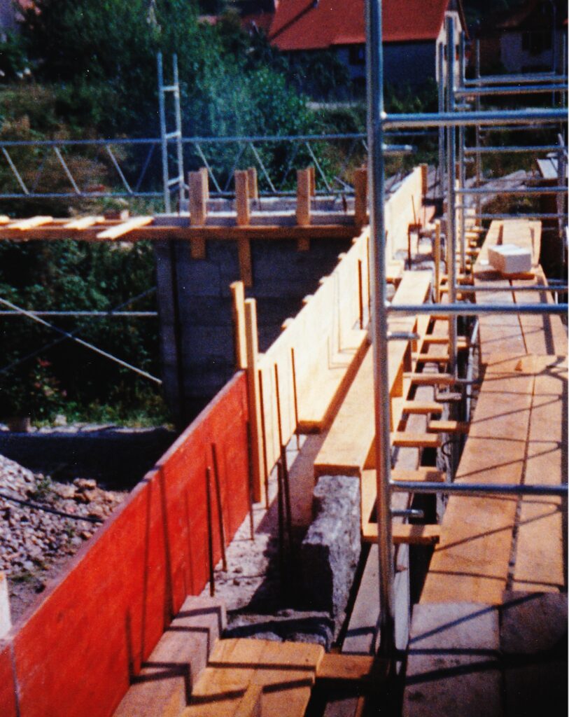 Construction site with wooden formwork framing a wall and metal scaffolding nearby